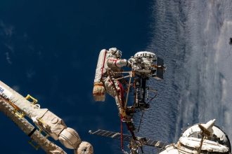 O cosmonauta da Roscosmos, Sergey Ryzhikov, é retratado no final do braço robótico europeu enquanto trabalha em uma câmera de alta‑resolução durante uma caminhada espacial de seis‑ horas e nove‑ minutos fora da Estação Espacial Internacional em 16 de outubro de 2025. Crédito: NASA